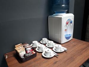 a table with cups and saucers and a coffee maker at Grand Plaza Boutique Hotel in Karawang