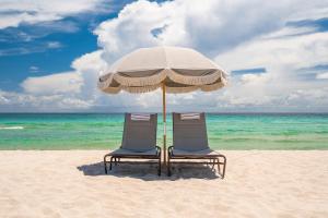 twee stoelen en een parasol op een strand bij The Plymouth South Beach in Miami Beach