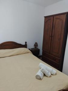 two rolled up towels sitting on a bed with a dresser at Yatale II in Chascomús