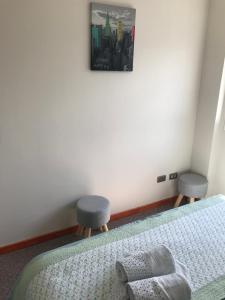 1 dormitorio con 1 cama con 2 sillas y una foto en la pared en Departamento en Pelluco, Puerto Montt, en Puerto Montt