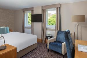 um quarto de hotel com uma cama e uma cadeira em The Scholar em Edimburgo