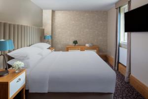 a bedroom with a large white bed and a flat screen tv at The Scholar in Edinburgh
