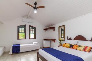 a bedroom with two beds and a ceiling fan at Casa Aldeia Paraty in Paraty