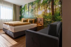 a bedroom with a bed and a couch and trees mural at Hotel am Sonnenlandpark in Lichtenau