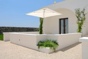a white table with an umbrella and a plant at Masseria Bagnara Resort & Spa in Marina di Lizzano