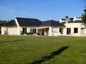 una gran casa blanca con un gran patio verde en Villa de 5 chambres avec piscine privee jacuzzi et jardin clos a Saint Nic en Saint-Nic