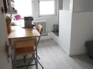 uma cozinha com uma mesa e uma secretária com um computador portátil em L'Orangerie, studio em Estrasburgo