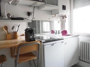 uma pequena cozinha com um lavatório e uma mesa em L'Orangerie, studio em Estrasburgo