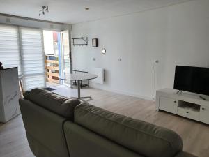 a living room with a couch and a table and a tv at Flobart grand appartement à Sangatte au rdc et à 30 metres de la plage in Sangatte
