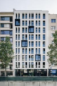 a white building with black windows in a city at The ASH in Antwerp