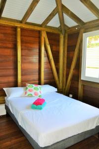 een slaapkamer met een wit bed, houten wanden en een raam bij Maison Piscine personnelle vue mer COSY in Le Marin