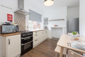 a kitchen with white cabinets and a table with a microwave at Charles Alexander Short Stay - Ansdell House in Blackpool