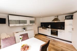 a kitchen with white cabinets and a table with flowers on it at Strandbrise in Hofe