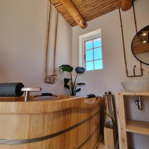a wooden tub in a bathroom with a sink at De Kombuys in Oudtshoorn