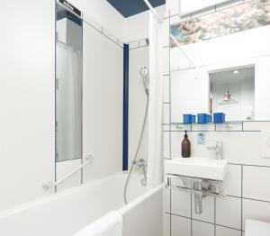 a white bathroom with a shower and a sink at NunoHotel in Cologne