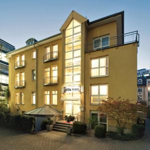 a yellow building with an umbrella in front of it at Villa Hotel Frankfurt by MZ HotelCollection in Frankfurt