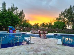 a pool at a resort with a sunset in the background at Arena Carneiros Hotel by AFT in Tamandaré