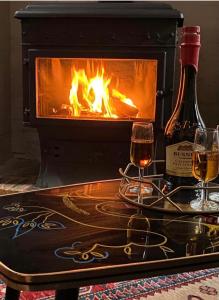 eine Flasche Wein und zwei Gläser auf dem Tisch vor dem Kamin in der Unterkunft Maison de la Calonne - Riverside house & terrace in Cormeilles + 34 Fotos