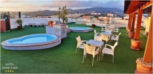 a patio with chairs and a hot tub on a roof at Hotel Xaine Park in Lloret de Mar