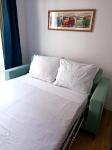a bed with white sheets and a picture on the wall at Charmant Studio Refait à neuf Centre de Tours in Tours