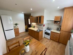 a kitchen with wooden cabinets and a table with flowers at Apartmán Hlboký potok in Vysoke Tatry - Tatranska Lomnica.