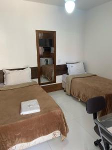 a hotel room with two beds and a mirror at Pousada Pinheiro in Campos dos Goytacazes