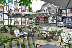 an outdoor patio with tables and chairs and umbrellas at Landhotel Albers in Schmallenberg