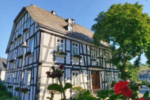 a black and white building with flowers in front of it at Landhotel Albers in Schmallenberg