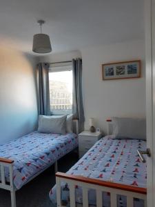 een slaapkamer met 2 aparte bedden en een raam bij The Getaway - Modern 2 Bedroom Brixham Bungalow with sea peeps in Brixham