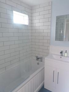 a white bathroom with a tub and a sink at The Getaway - Modern 2 Bedroom Brixham Bungalow with sea peeps in Brixham