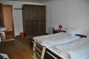 2 Betten in einem Zimmer mit Waschbecken und Tisch in der Unterkunft Hostel Engelberg in Engelberg