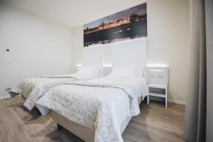 twee bedden in een witte kamer met een schilderij aan de muur bij Cascina Speranza Hotel in Riva presso Chieri