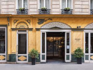 a yellow building with doors and plants in front at New Hotel Roblin in Paris