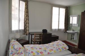 1 dormitorio con cama, escritorio y lavamanos en Hostel Engelberg, en Engelberg