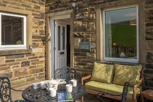 a patio with a table and a couch and a window at 1 Riverside Cottage in Burnsall
