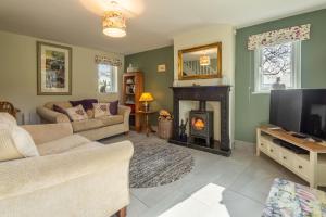 a living room with a fireplace and a tv at 1 Riverside Cottage in Burnsall