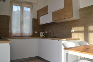 una cucina con armadi bianchi, lavandino e finestra di Casa Rosetta a Noli
