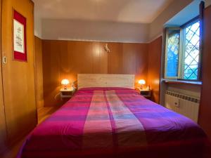 - une chambre avec un grand lit et un couvre-lit violet dans l'établissement Casa Loria - Appartamento con Giardino, à San Martino di Castrozza