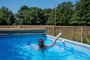 a girl in a swimming pool holding a toy at Heather Cottage in Brockenhurst