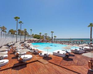 una piscina con sillas y sombrillas y la playa en Marbella Hills en Marbella