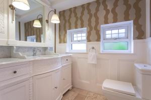 a white bathroom with a sink and a mirror at Stunning 4 bedroom country house - Hot Tub & Sauna in Glasgow +17 photos