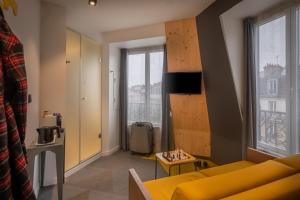 a living room with a yellow couch and a window at Urban Bivouac Hotel in Paris