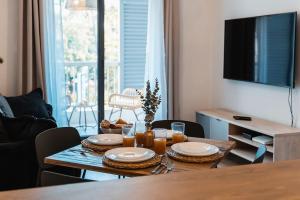uma mesa de jantar com pratos e copos e uma televisão em Studio Les Aigrettes em Saint-Gilles-les-Bains