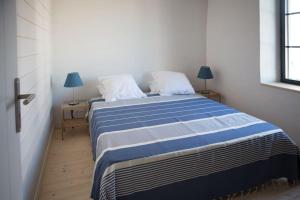 um quarto com uma cama azul e branca com 2 candeeiros em Les Maisons de l'Olivette em La Couarde-sur-Mer