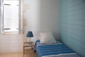 um quarto com uma cama, um candeeiro e uma janela em Les Maisons de l'Olivette em La Couarde-sur-Mer