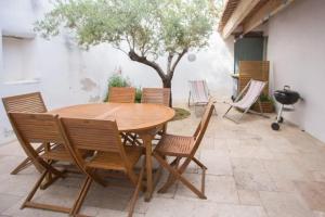 a wooden table and chairs on a patio at Les Maisons de l'Olivette in La Couarde-sur-Mer