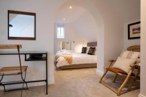 1 dormitorio con cama, espejo y silla en Nutmeg House, en Lymington