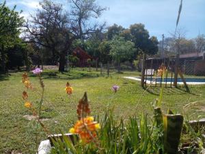 a garden with flowers in the grass with a playground at Cabaña La Calandria in San José del Rincón