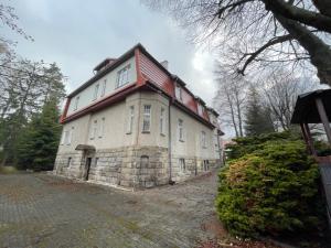 an old stone house with a red roof at Willa pod Bukami in Polanica-Zdrój