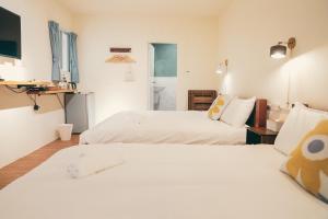 two beds in a room with white walls at Juran B&B in Nanwan